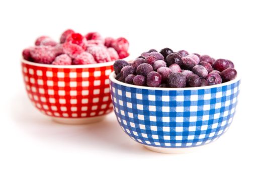 frozen raspberries and bilberries in the bowl, on a white background