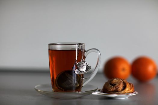 cup of strong black tea biscuit and two orange