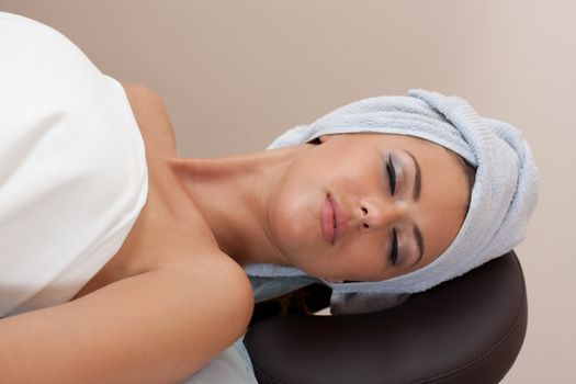 young woman in a spa salon lays on a table having closed eyes