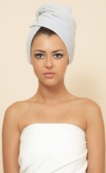 young woman in a bedsheet and with a towel on a head in spa salon
