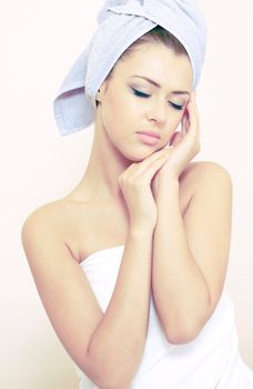 young woman in a bedsheet and with a towel on a head in spa salon