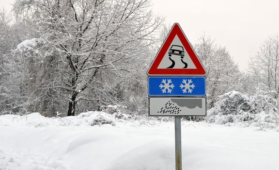 Slippery road sign in snow. Severe weather conditions