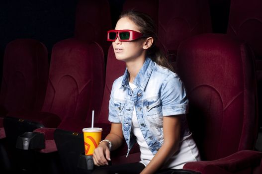 young woman sitting alone in the cinema and watching a movie