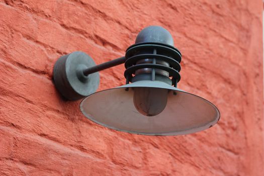 An old fashioned street lamp on a red wall.