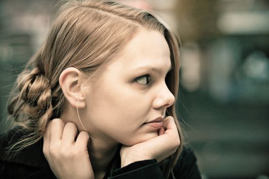 Profile of a pensive young blond woman, desaturated, film grain