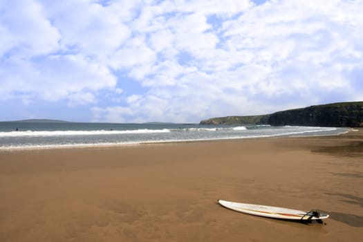 sandy golden beach with lone surfboard lying on the sand in ballybunion county Kerry Ireland