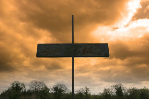 metal cross in a christian church graveyard against a red stormy sky