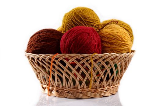wicker basket with colorful balls of wool on a white background 