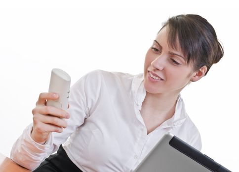 Portrait of a happy young woman looking at phone in front of a laptop computer, high key, focus on eyes