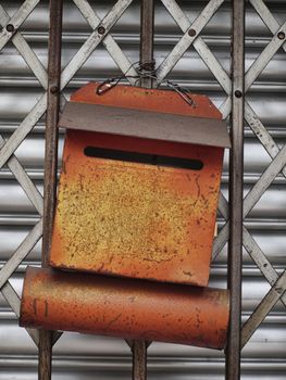 Rusty orange letter box on a metallic gate