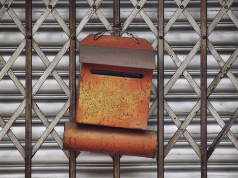 Rusty orange letter box on a metallic gate