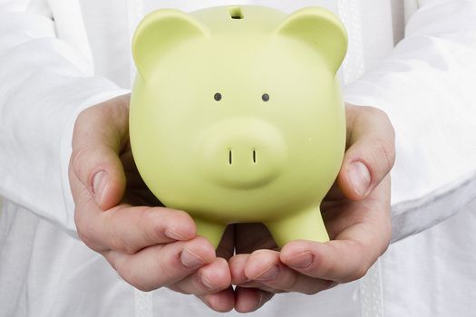 Close-up photograph of a green piggy bank in man's hands.