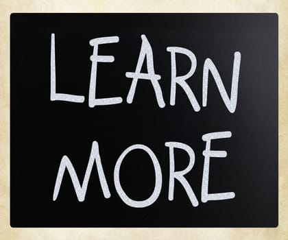 "Learn More" handwritten with white chalk on a blackboard