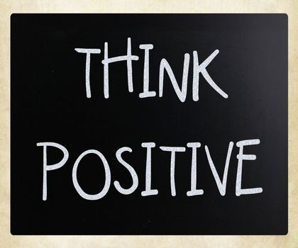 "Think positive" handwritten with white chalk on a blackboard