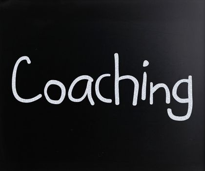 "Coaching" handwritten with white chalk on a blackboard