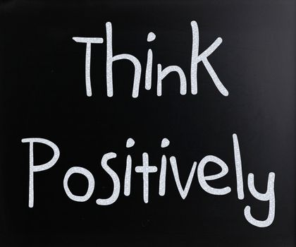 "Think Positively" handwritten with white chalk on a blackboard