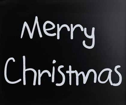 "Merry Christmas" handwritten with white chalk on a blackboard