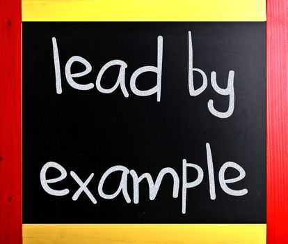 "Lead by example" handwritten with white chalk on a blackboard