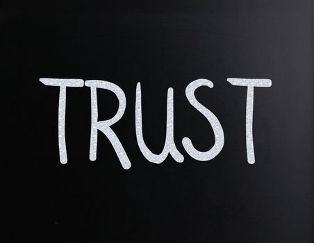 The word "Trust" handwritten with white chalk on a blackboard