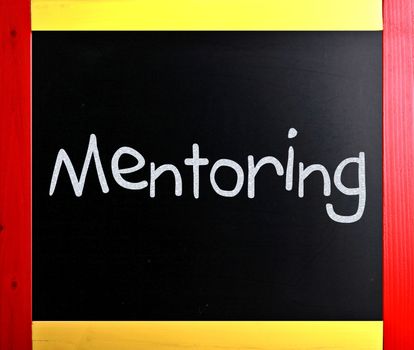 The word "Mentoring" handwritten with white chalk on a blackboard