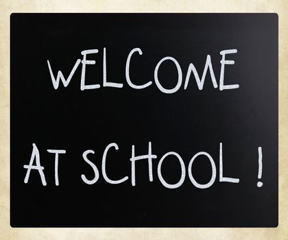 "Welcome at school" handwritten with white chalk on a blackboard
