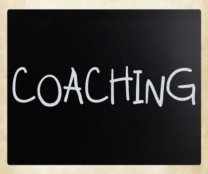 "Coaching" handwritten with white chalk on a blackboard