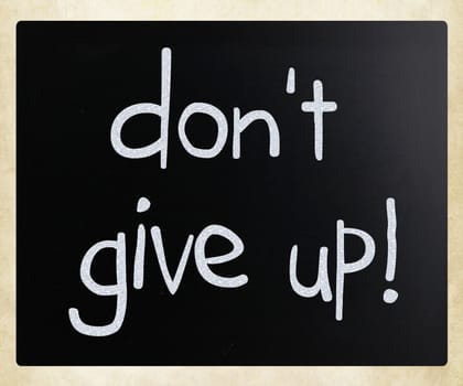 "Don't give up" handwritten with white chalk on a blackboard