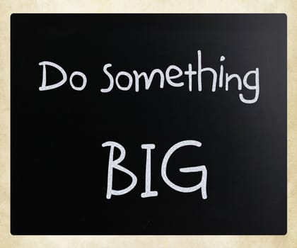 "Do something big" handwritten with white chalk on a blackboard