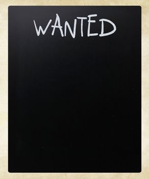 "Wanted" handwritten with white chalk on a blackboard