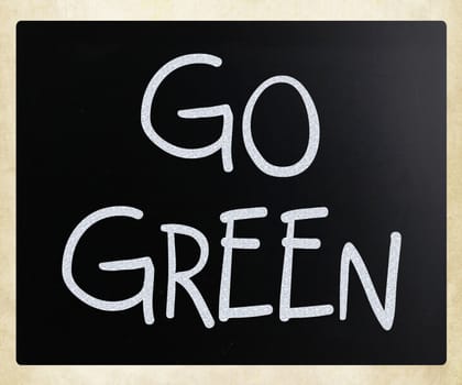 "Go green" handwritten with white chalk on a blackboard