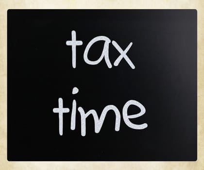 "Tax time" handwritten with white chalk on a blackboard