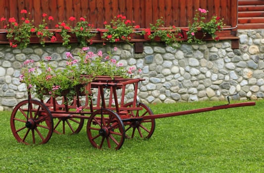 Nice and colorful garden with a wooden wagon.