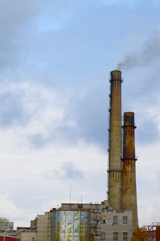 Two old factory smokestack tube against the cloudy sky