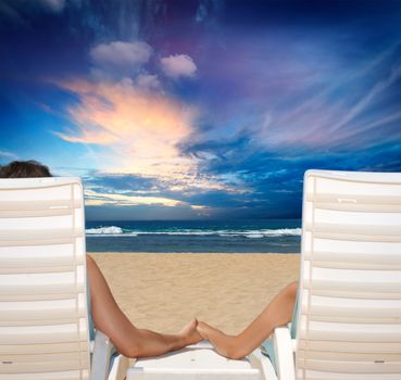 Couple in beach chairs holdi hands on beach  and enjoy sunset