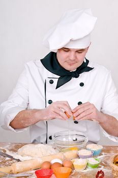 Chef breaks an egg into a bowl