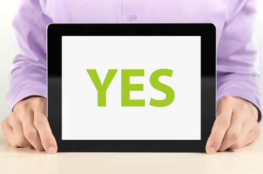 Manager holding tablet pc with "YES" text on screen.