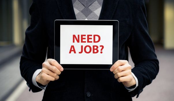 Business man holding tablet pc with "Need a job?" text on screen.