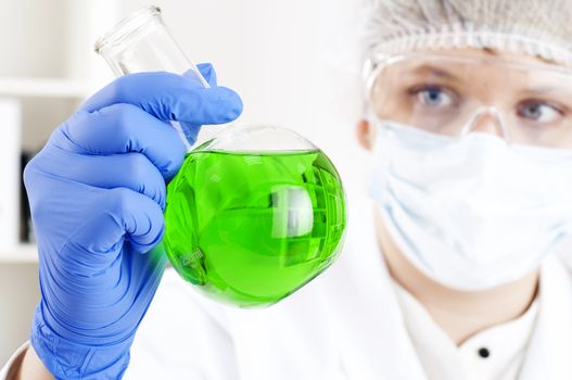 female chemist mixing liquids in test tubes, working in lab