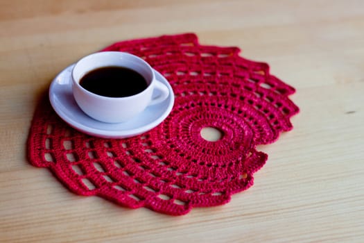 A coffee cup on red napkin on wooden table
