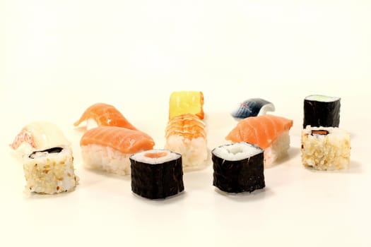 Japanese sushi with fresh salmon, shrimp, carrots and cucumber on a light background