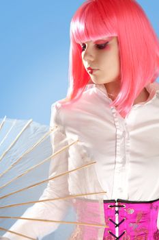 Young woman with oriental make-up, and umbrella, studio shot over blue background 