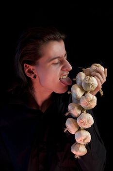 Vampire licking garlic, red horror light, isolated on black background 