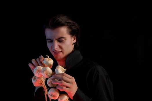 Handsome vampire doesn�t like the garlic, isolated on black background 