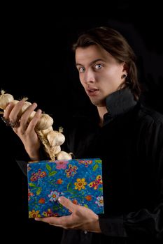 Funny vampire with gift box taking out garlic, isolated on black background 