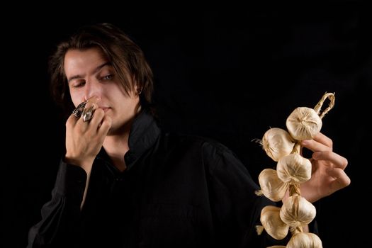 Aristocratic vampire doesn�t like the smell of garlic, isolated on black background 