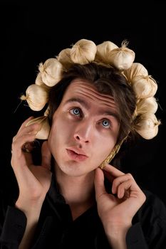 Funny shot of vampire with scary blue eyes with garlic on his head, isolated on black background 