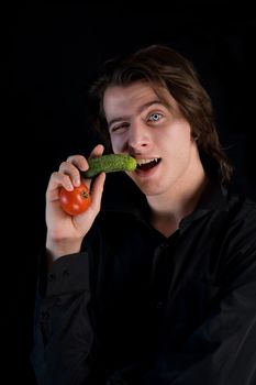 Funny vegetarian vampire with vegetables, healthy eating concept, isolated on black background 