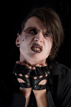 Expressive gothic boy with artistic make-up and blue lenses, isolated on black background 