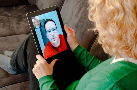 Middle-aged woman using video telephony on digital tablet pc