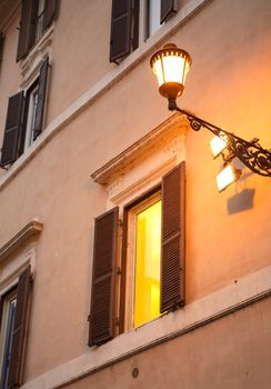 Vintage lantern on the wall near glowing window